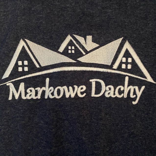Wyhaftowane logo firmy dekarskiej 'Markowe Dachy' na ciemnym materiale. Grafika przedstawia trzy dachy z oknami i kominem.