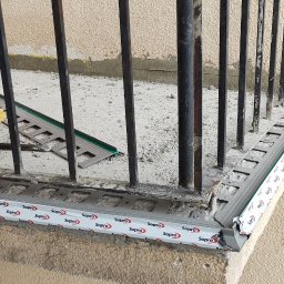 Tomasz Czaja - Montaż profilu okapowego na balkonie z widocznymi narzędziami i szczotką do czyszczenia, etap prac wykończeniowych.