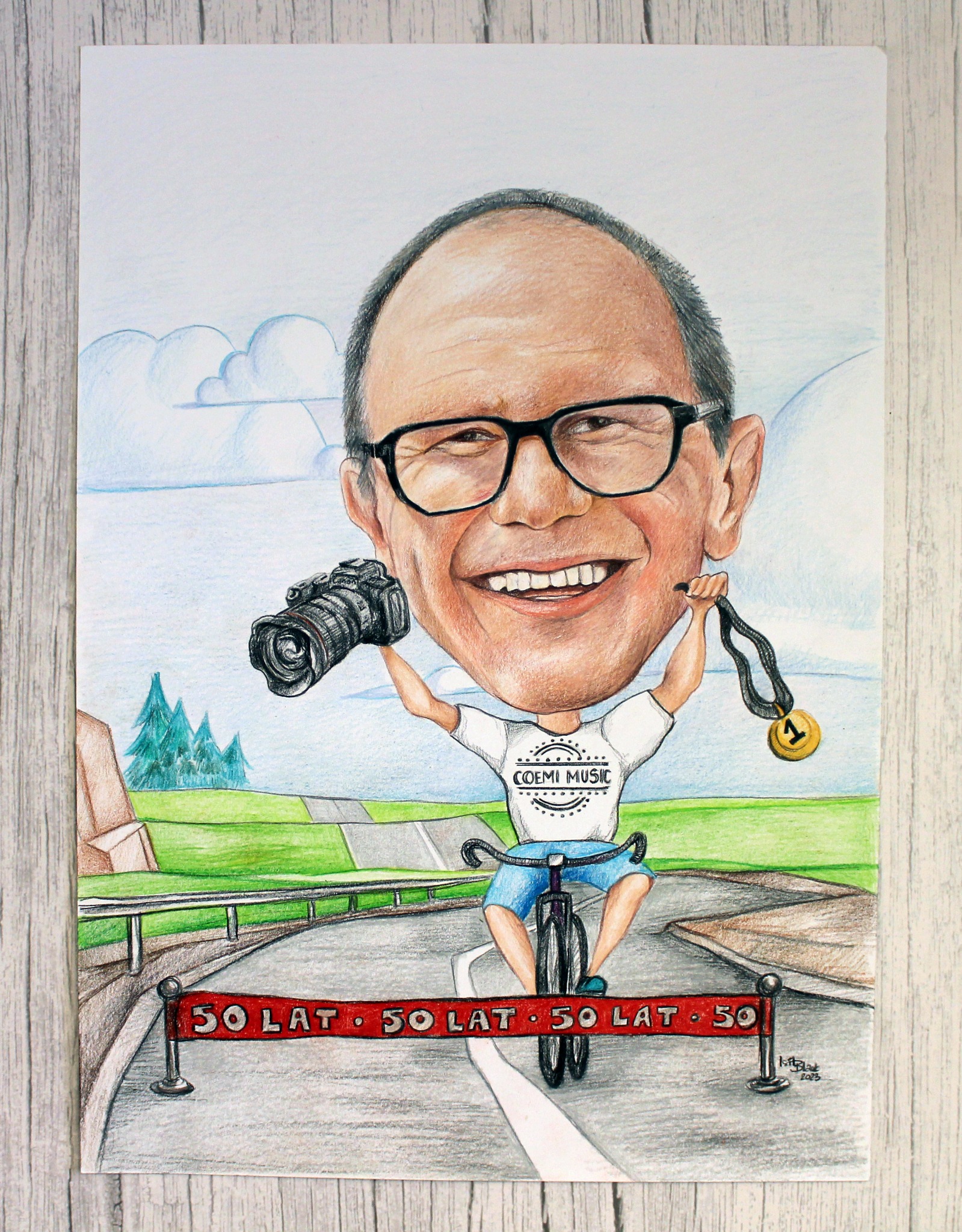 Ręcznie rysowana karykatura uśmiechniętego mężczyzny na rowerze, trzymającego aparat fotograficzny i złoty medal z numerem 1, z napisem '50 lat' na mecie.