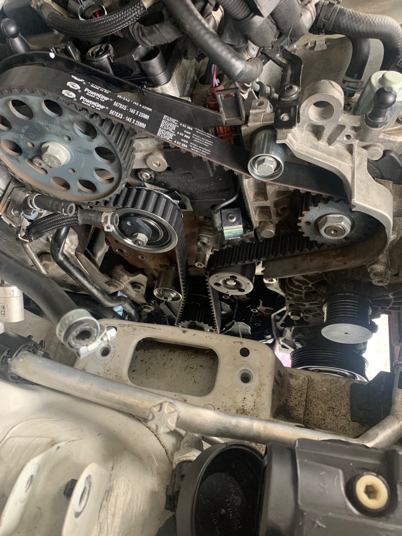 Widok z góry na silnik samochodowy z widocznym paskiem rozrządu PowerGrip 5678XS-145 x 25mm, kołami zębatymi i elementami mocującymi podczas wymiany lub serwisu.