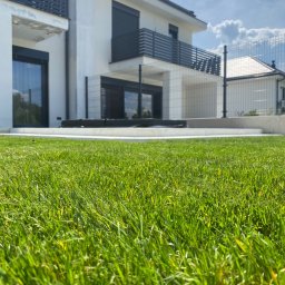 TRZPIOT COMPANY Aleksandra Trzpiot - Wykonanie tarasu z bloków schodowych i płyt betonowych + realizacja ogrodu. Na zdjęciu widoczny taras i trawnik z rolki