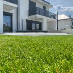 Wykonanie tarasu z bloków schodowych i płyt betonowych + realizacja ogrodu. Na zdjęciu widoczny taras i trawnik z rolki