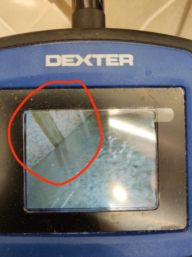 Ekran kamery inspekcyjnej marki Dexter pokazuje wnętrze rury z widocznym zanieczyszczeniem i uszkodzeniem, prawdopodobnie podczas procesu udrażniania.