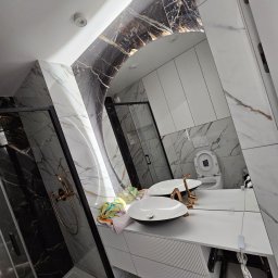 A.M.G. KATOWICE SPÓŁKA Z OGRANICZONĄ ODPOWIEDZIALNOŚCIĄ - Nowoczesna łazienka z marmurowymi płytkami, kabiną prysznicową typu walk-in, podwójną umywalką i dużym, owalnym lustrem z podświetleniem.