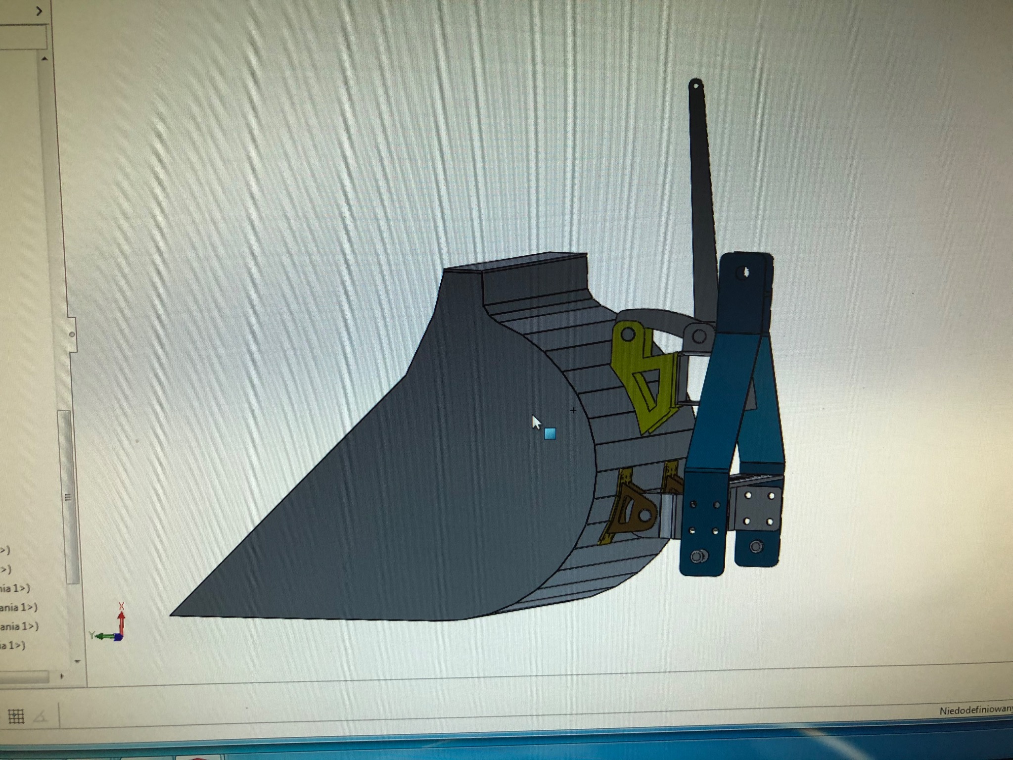 Projekt 3D łyżki koparki z widocznymi elementami mocującymi, wyświetlany na ekranie komputera.