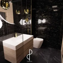 Elegancka łazienka z czarnymi marmurkowymi płytkami, wiszącymi złotymi lampami i umywalką z drewnianą szafką, oświetlona dekoracyjnym lustrem z okrągłym światłem.