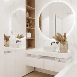 Nowoczesna łazienka z okrągłym lustrem podświetlanym LED, białą umywalką nablatową i marmurowym blatem, uzupełniona o drewniane półki z kosmetykami i dekoracyjnym suszem w metalowym koszyku.