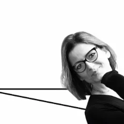 Portret kobiety w okularach, z zamyślonym uśmiechem, na białym tle z geometryczną linią, w czerni i bieli.