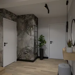 Wnętrze przedpokoju z tapetą w motywy roślinne, drewnianą podłogą i minimalistycznymi drzwiami, oświetlone punktowym reflektorem i wiszącą lampą.