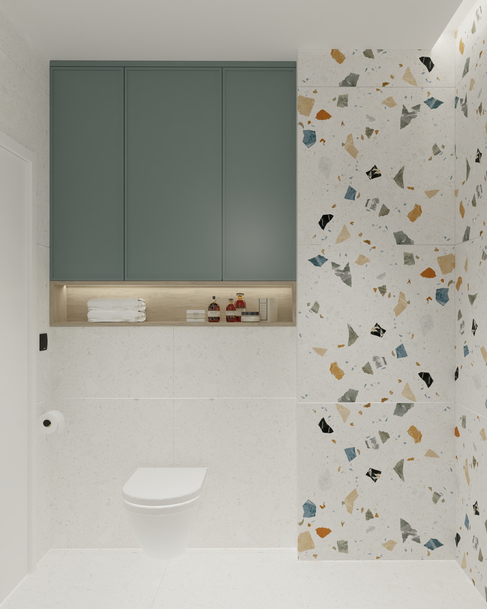 Nowoczesna łazienka z toaletą, zielonymi szafkami nad półką z oświetleniem LED, ręcznikami i kosmetykami, wykończona płytkami imitującymi lastryko w odcieniach bieli, szarości, czerni, niebieskiego...