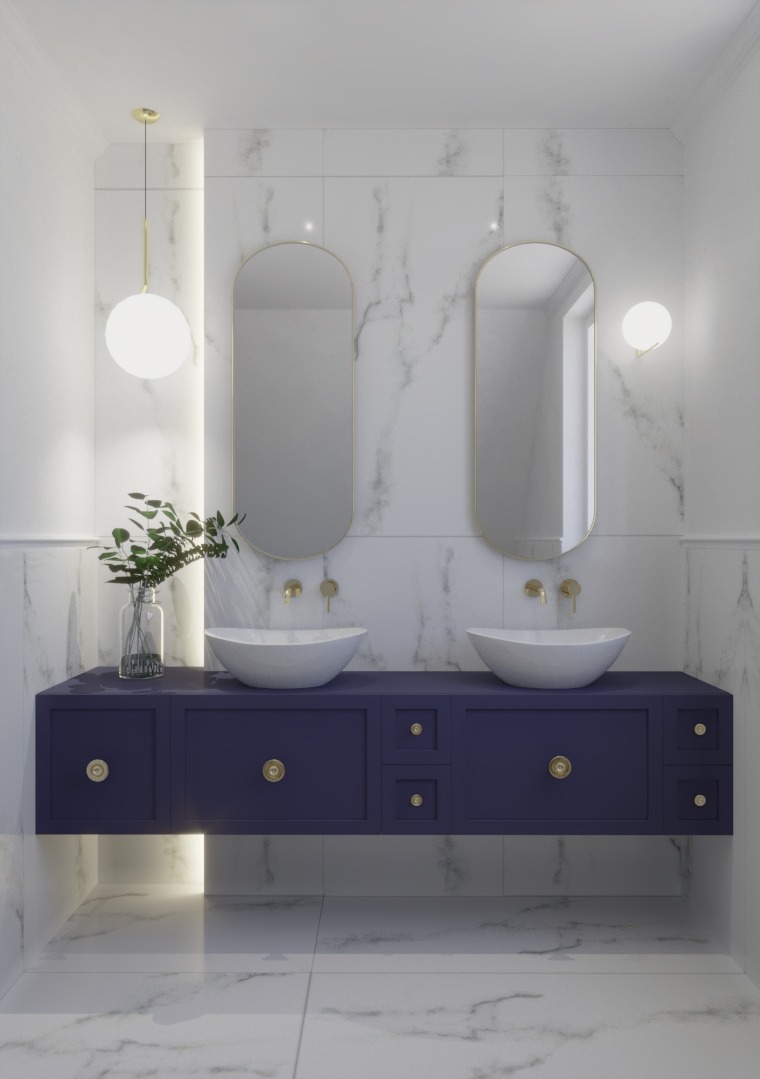 Nowoczesna łazienka z podwójną umywalką nablatową, owalnymi lustrami w złotej ramie, granatową szafką z złotymi uchwytami, marmurowymi płytkami i kulistymi lampami.