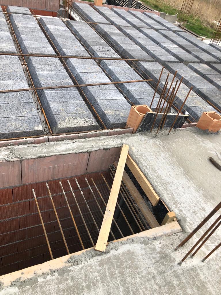 Wykonywanie stropu Teriva z betonowaniem, widoczne pustaki stropowe, zbrojenie i otwór w stropie z deskowaniem.