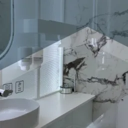 Nowoczesna łazienka z marmurowymi płytkami, białą umywalką nablatową, dozownikami mydła i koszem na śmieci z pedałem; widoczny fragment toalety; logo firmy 'ASM Wrocław Cleaning' na górze.