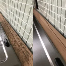 Porównanie stanu fragmentu blatu kuchennego przed i po czyszczeniu, widoczny brudny blat z boku zlewu oraz czysty blat po prawej stronie, w tle mozaika z jasnych płytek.
