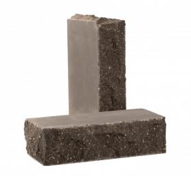 Dwie cegły klinkierowe w odcieniach szarości i brązu. Jedna cegła stoi pionowo, a druga leży płasko na niej. Tekstura cegieł jest szorstka i nieregularna.