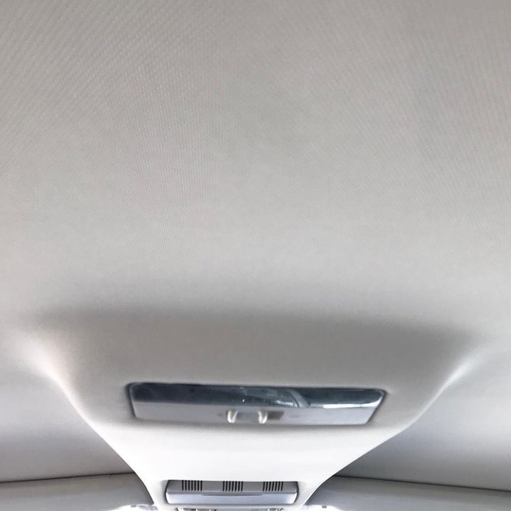 Jasna podsufitka samochodu z widocznym oświetleniem wewnętrznym i kratką wentylacyjną, sfotografowana z dołu.