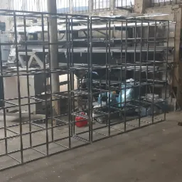 Metalowa konstrukcja szkieletowa z kwadratowych profili, prawdopodobnie regał, w warsztacie.