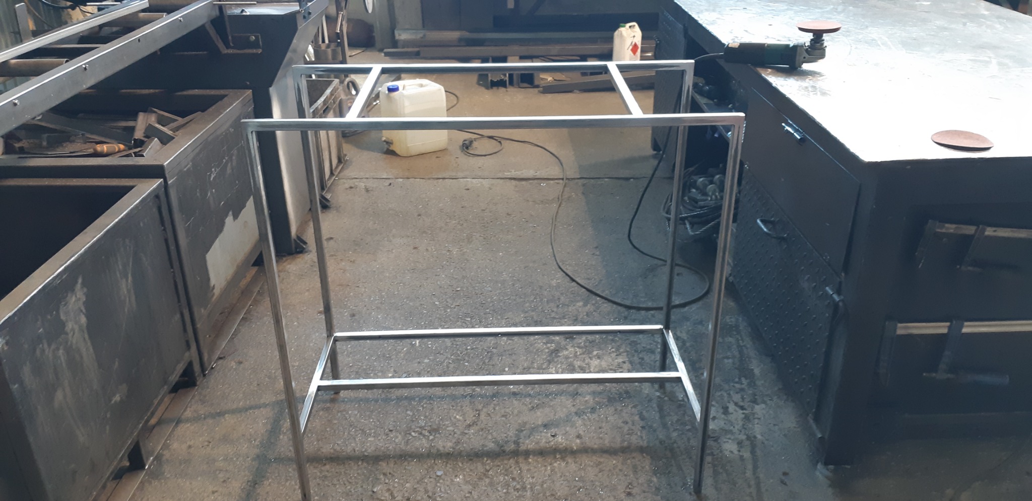 Szkielet metalowej konstrukcji spawanej z profili, widoczny w warsztacie obróbki metali, z narzędziami i materiałami w tle.