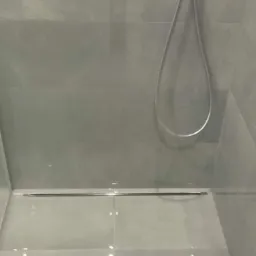 Nowoczesna kabina prysznicowa z szarymi płytkami, chromowaną armaturą i odpływem liniowym w podłodze