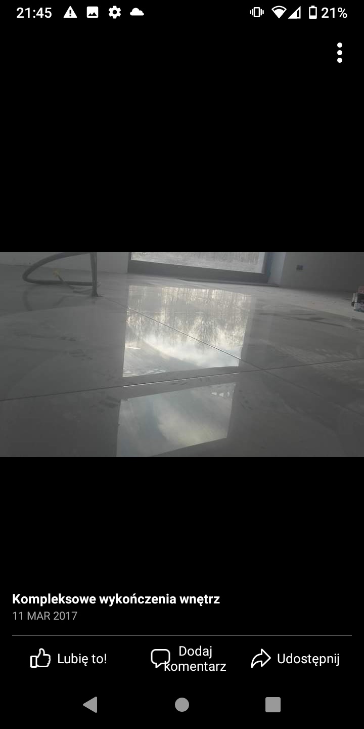 Błyszcząca, jasnoszara podłoga z płytek w Przyszowej, odbijająca światło okna i otoczenie, widoczne fugi.