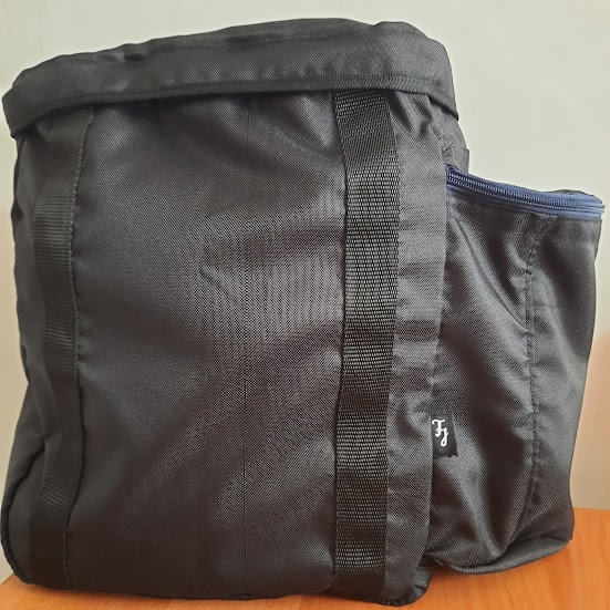 Czarna torba z nylonu z dwoma paskami wzmacniającymi i boczną kieszenią na zamek, widoczna metka z inicjałami.