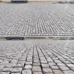 Rozległa powierzchnia wyłożona szarą kostką brukową, regularny wzór z widocznymi fugami, samochód w tle, ujęcie z dwóch perspektyw.