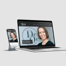 Laptop i smartfon prezentują stronę internetową Dental Design z uśmiechniętą kobietą, minimalistyczny design, czarne menu, białe tło.