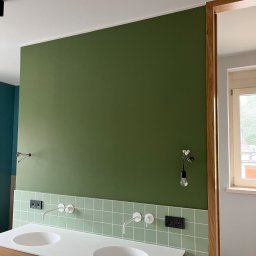 MARK-MAL Marek Leśniak - Nowoczesna łazienka z zieloną ścianą, białą umywalką nablatową i drewnianą szafką. Widoczne płytki w odcieniach zieleni i minimalistyczna armatura.