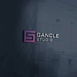 GANCLE Studio Jakub Pisula - Logo 'GANCLE STUDIO' w kolorze fioletowo-białym, umieszczone na szklanej ścianie biura z widocznymi biurkami i krzesłami w tle.