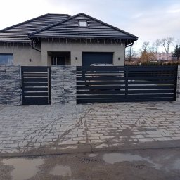 ALI-SPAW - Nowoczesna, pozioma brama wjazdowa i ogrodzenie z szarego metalu, z elementami dekoracyjnymi z betonu architektonicznego. Dom jednorodzinny w tle.