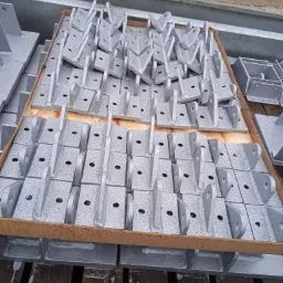 Szare, metalowe elementy konstrukcyjne w skrzyni transportowej, pokryte kroplami wody, ułożone równo w rzędach.