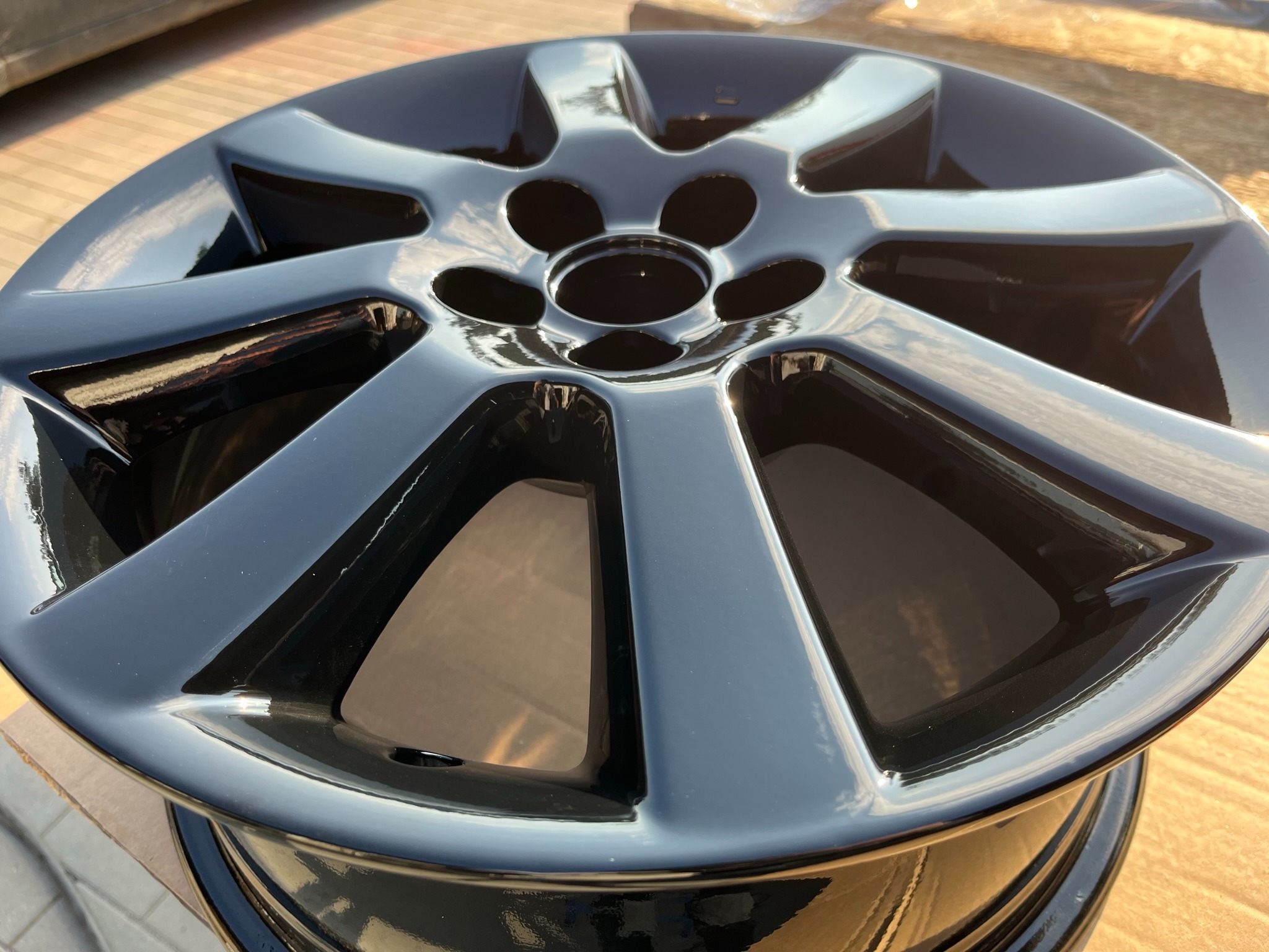 Błyszcząca, czarna felga aluminiowa po renowacji, z widocznymi refleksami światła na gładkiej powierzchni.