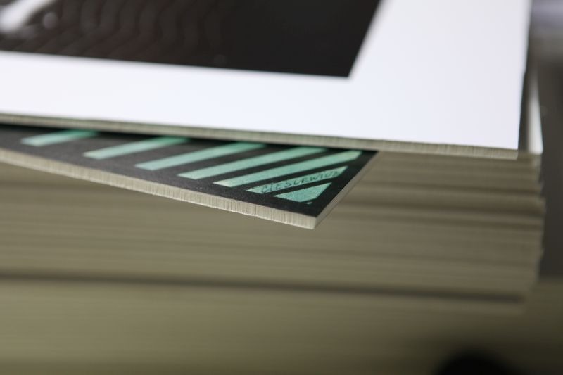 Stos wydrukowanych arkuszy z widocznym detalem krawędzi i nadrukowanym wzorem w paski z nazwiskiem 'CIESLEWICZ' w rogu.