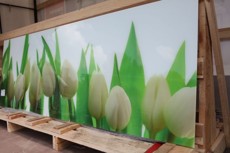 Duży panel z nadrukiem białych tulipanów i zielonych liści, zabezpieczony drewnianą ramą transportową.