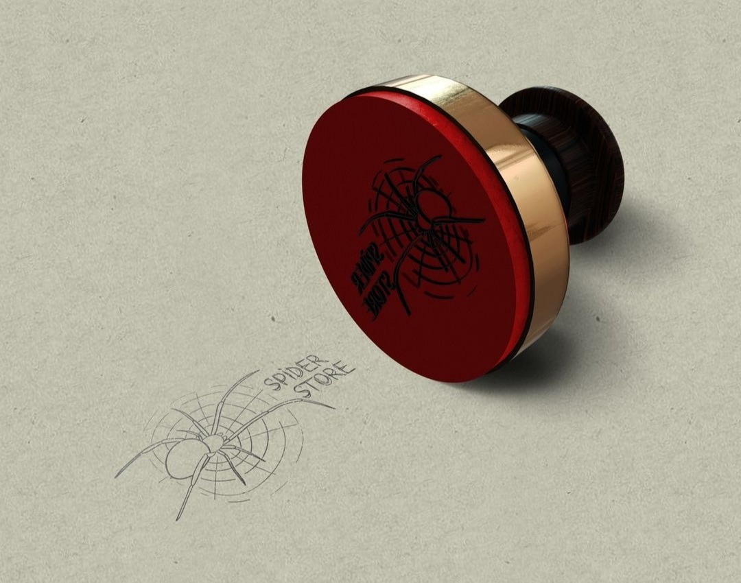 Stempel z czerwonym, okrągłym stemplem i drewnianą rączką, odbity wzór pająka z napisem 'Spider Store' na szarym tle.