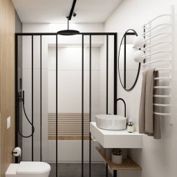 Coren Studio Design - Nowoczesna łazienka z kabiną prysznicową typu walk-in, umywalką nablatową i minimalistycznym oświetleniem punktowym. Uwagę zwraca drewniany akcent na ścianie i pod umywalką.