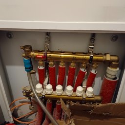 Rafał B - Rozdzielacz instalacji grzewczej podłączony do rur w szafce, widoczne zawory termostatyczne i rury w izolacji termicznej, marka Ferro.