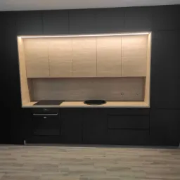 Nowoczesna kuchnia z czarnymi matowymi frontami i drewnopodobnymi szafkami górnymi podświetlonymi listwą LED, płyta indukcyjna i okrągły zlew w blacie.