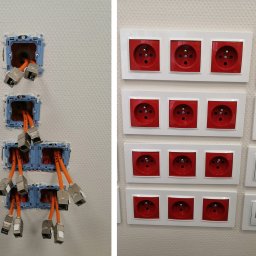 Voltro Łukasz Jeleniewski - Ściana z zamontowanymi gniazdami elektrycznymi DATA w czerwonych obudowach oraz gniazdami sieciowymi RJ45 w białych obudowach, po lewej stronie widoczne puszki instalacyjne z pomarańczowymi kablami...