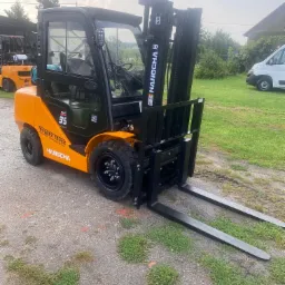 Nowy wózek widłowy spalinowy marki Hangcha w kolorze pomarańczowo-czarnym, model 3.5, stojący na żwirowym podłożu z widocznym logo Toolmex Truck.