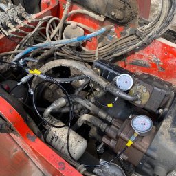 FS-Lechowicz Krzysztof Lechowicz - Silnik wózka widłowego poddawany diagnostyce, widoczne manometry podłączone do przewodów hydraulicznych, filtr oleju marki HIGHWAY.