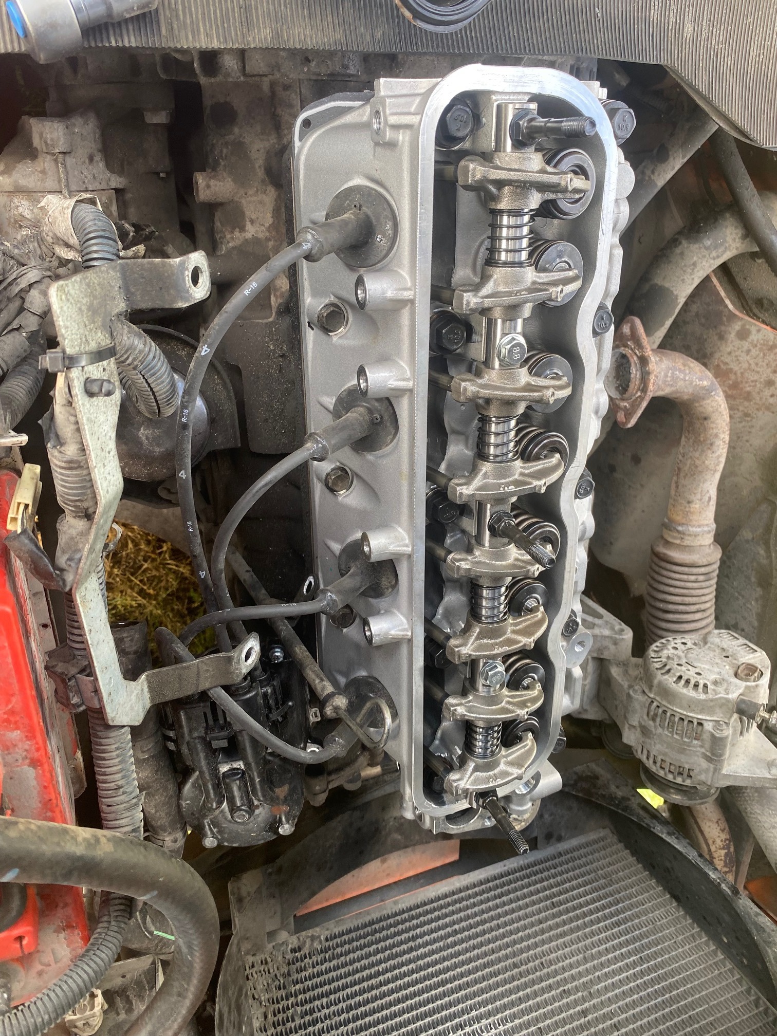 Silnik wózka widłowego z otwartą głowicą, widoczne elementy mechaniczne, przewody i złącza, w tle zabrudzone elementy konstrukcyjne pojazdu.