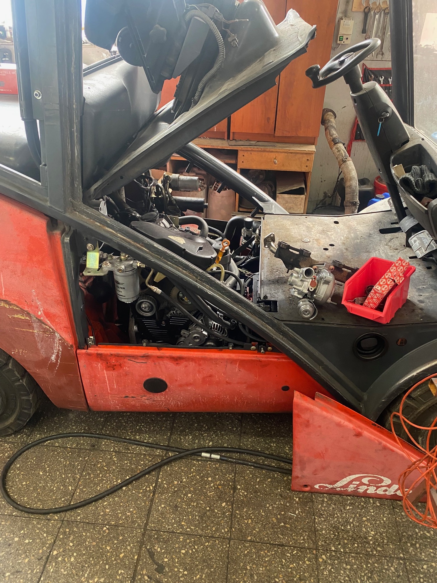 Otwarty silnik czerwonego wózka widłowego Linde podczas naprawy w Oleśnicy, widoczne narzędzia i części zamienne.