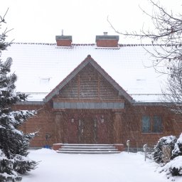 Dom jednorodzinny w stylu dworkowym.  Na zdjęciu- elewacja frontowa w oprawie zimowej. Elewacja wykonana z desek i cegły klinkierowej. 