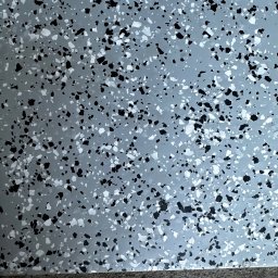 PHO HOME - Szara posadzka z czarnymi i białymi wtrąceniami, widoczny fragment krawędzi podłogi.