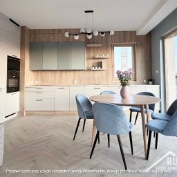 RUT-DOM Usługi Remontowo Wykończeniowe - Jasna kuchnia z drewnianymi akcentami, okrągłym stołem i błękitnymi krzesłami. Widok na miasto przez duże okno. Nowoczesne wykończenie wnętrz.