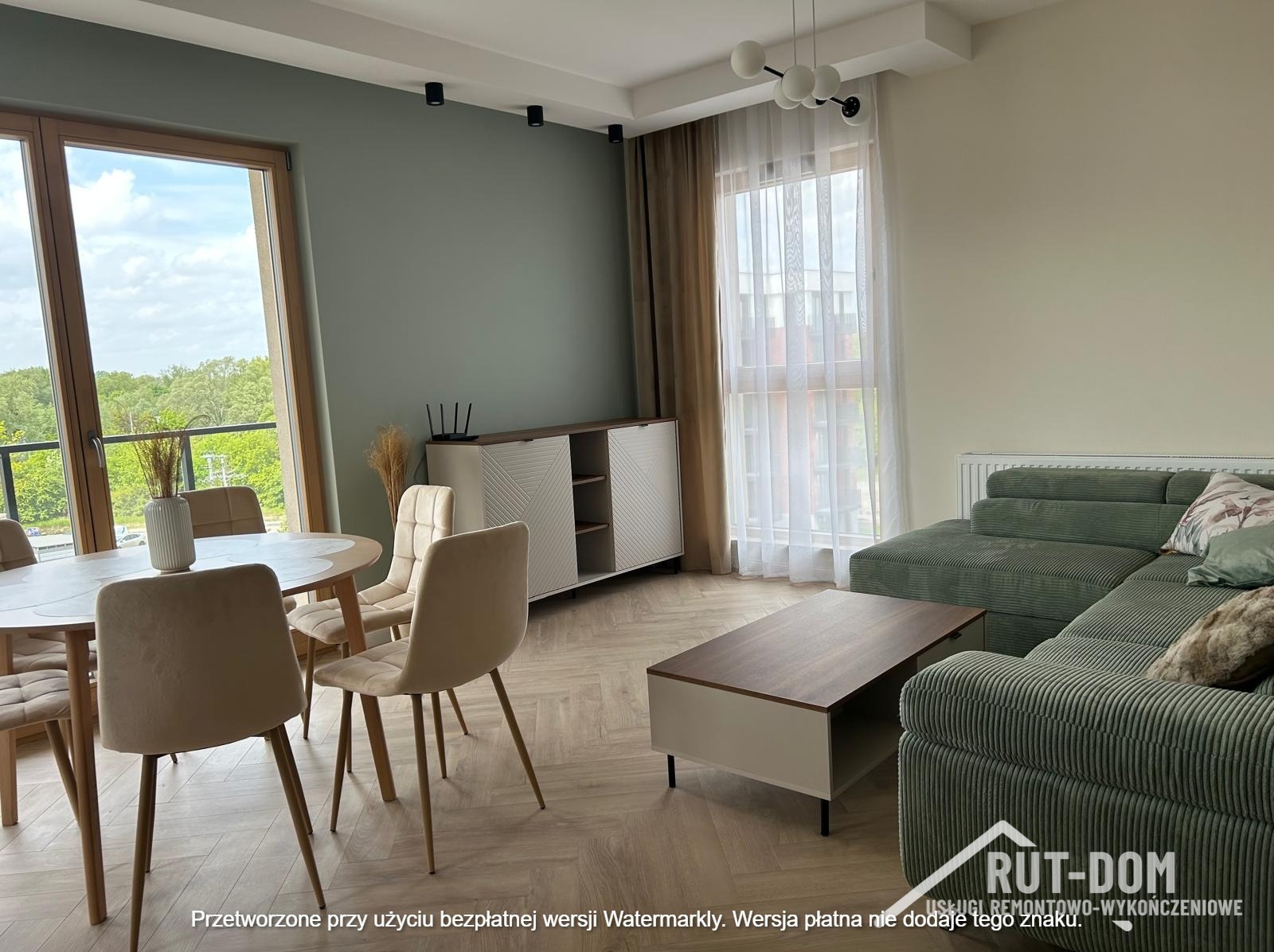 Jasne, przestronne wnętrze: stół z krzesłami, komoda z dekoracją, sofa i stolik kawowy. Parkiet w jodełkę. Widok z okna na zieleń. Nowoczesny design.