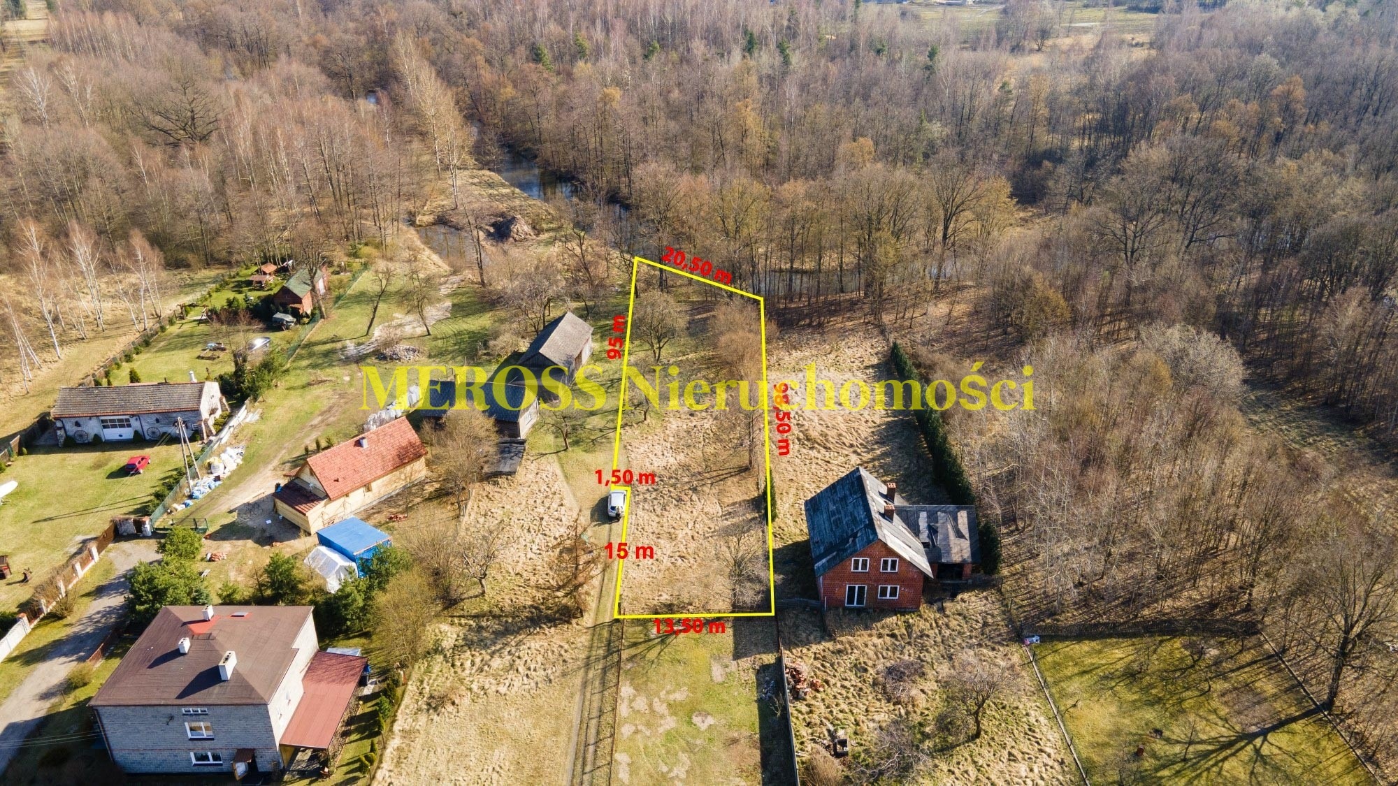 Działka budowlana z naniesionymi wymiarami i granicami, widok z drona, otoczona drzewami i zabudową jednorodzinną.