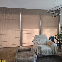 Mariusz - Beżowe, poziome  panele okienne w salonie z ceglaną ścianą i parkietem w jodełkę. Wnętrze dopełnia designerska lampa i dekoracje.