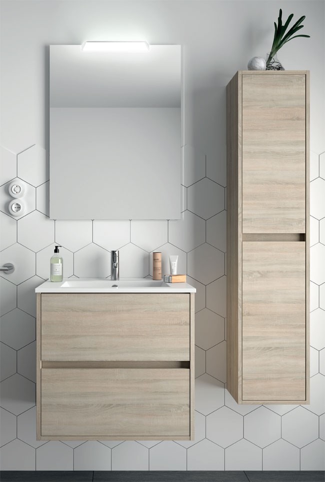 Nowoczesna łazienka z szafką pod umywalką z jasnego drewna, lustrem z oświetleniem LED i wysoką szafką wiszącą, uzupełniona białymi heksagonalnymi płytkami ściennymi i minimalistycznymi akcesoriami.